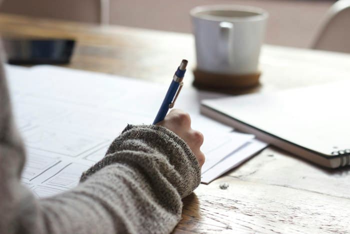 A learner taking handwritten notes beside a laptop